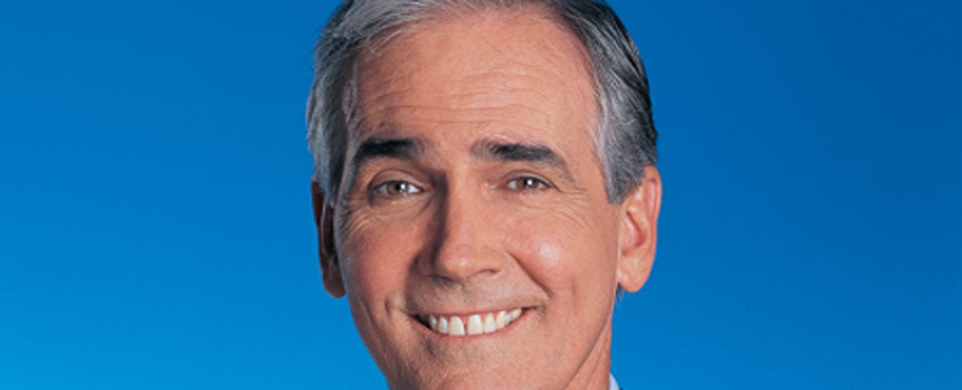 A man with grey hair and white teeth smiling.