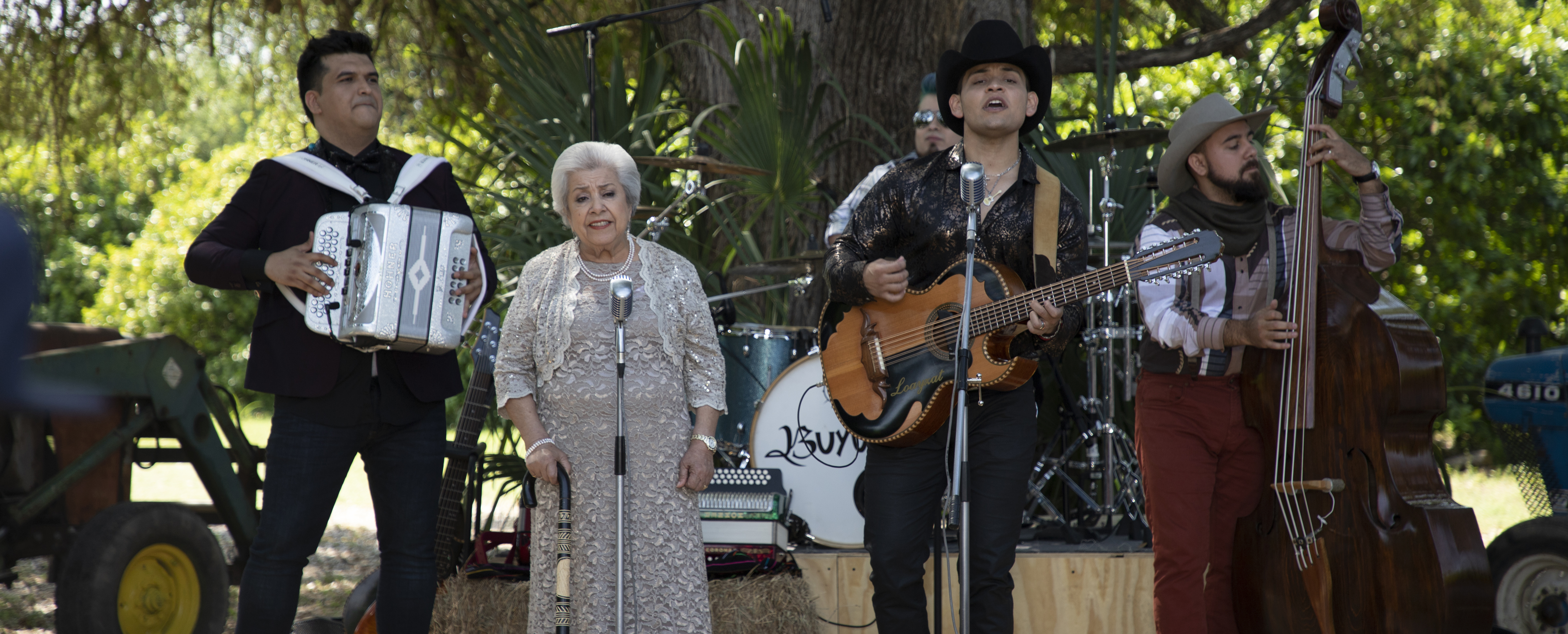 A man and woman sing into microphones while playing guitar.